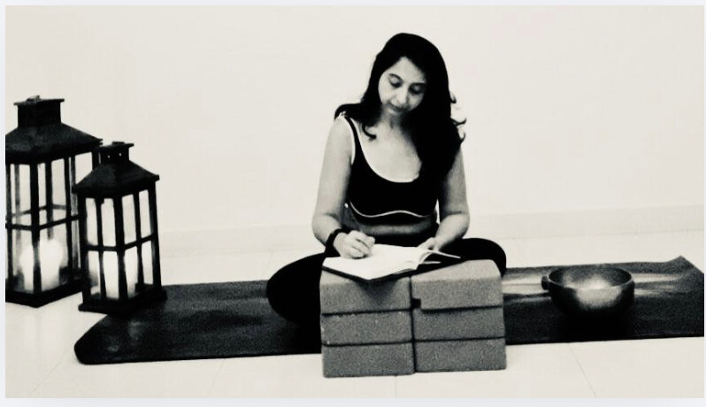 Karuna Grover journaling on the mat beside lanterns and a singing bowl
