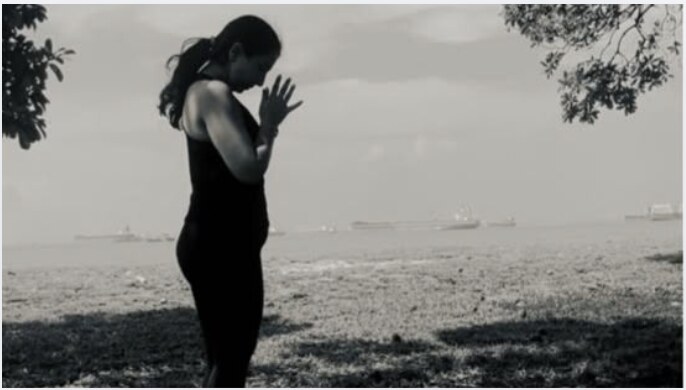 Karuna Grover standing in a prayer pose, seaside