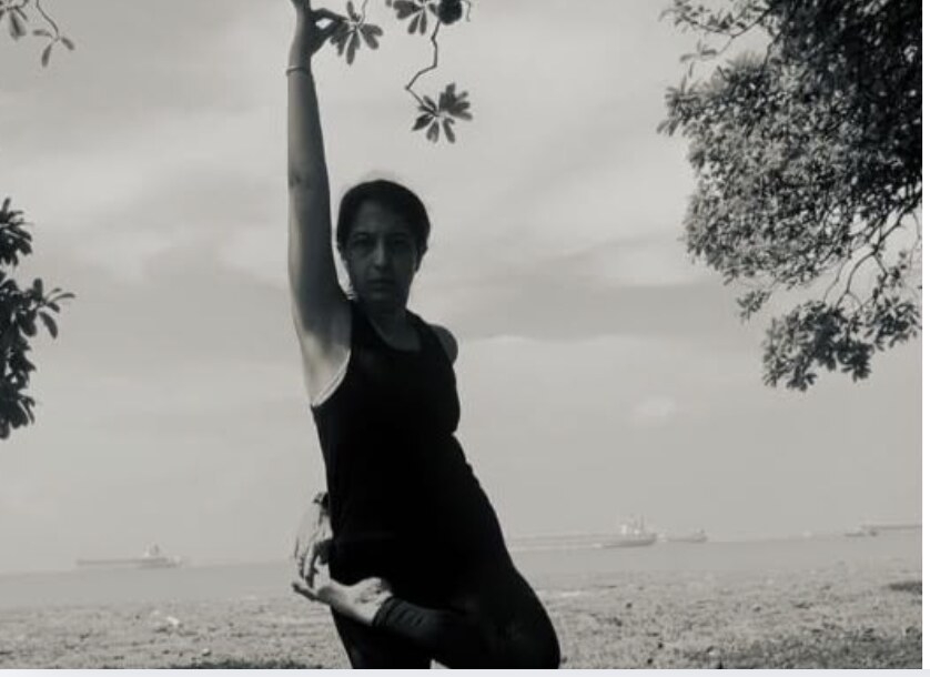Karuna Grover in a standing balance pose, seaside